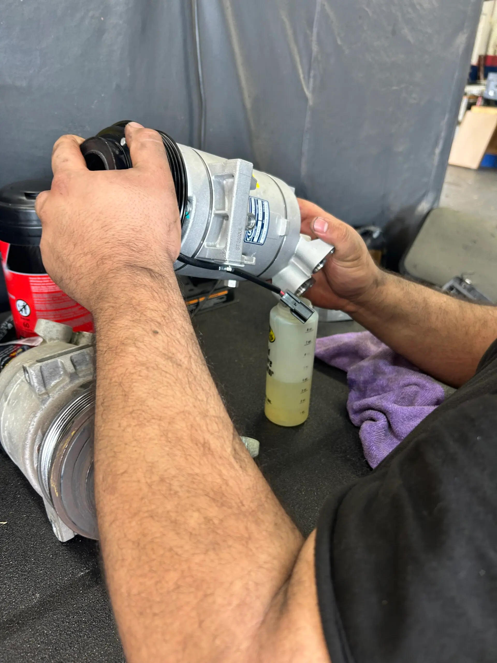 Technician preparing replacement AC compressor during repair in Houston, TX