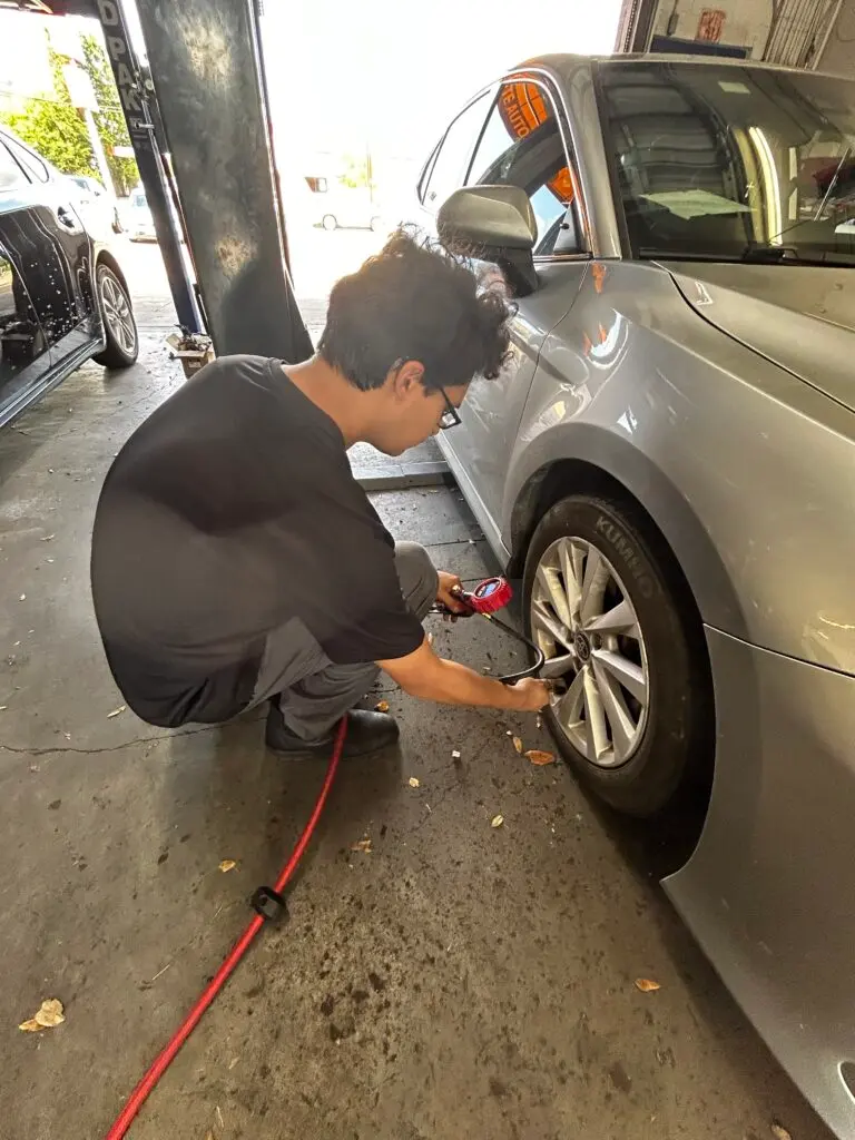 Technician checking tire pressure during a back-to-school vehicle check