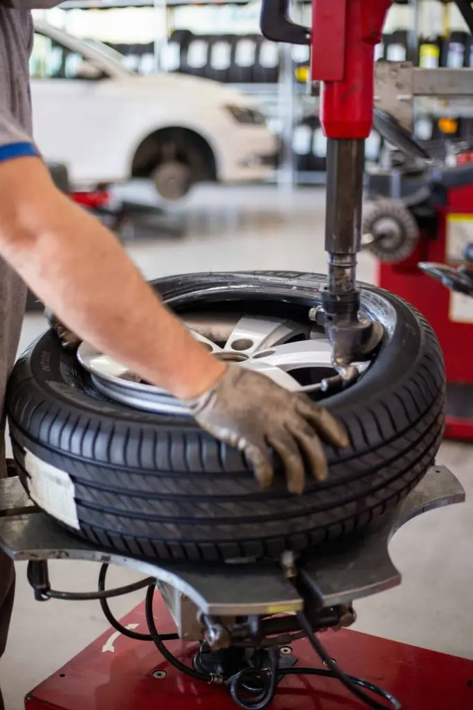 Mechanic operating tire mounting machine with a close-up of a tire, emphasizing tire maintenance for vehicle safety and performance.
