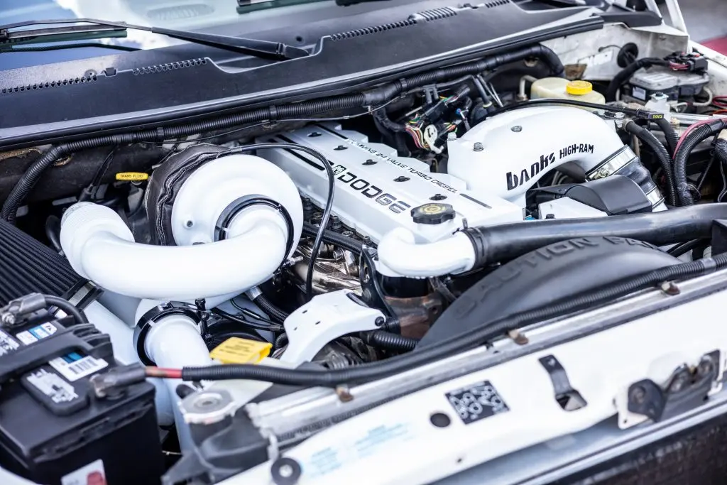 Dodge engine compartment featuring high-performance components, including Banks High-Ram intake and turbocharger, highlighting essential maintenance for optimal vehicle performance.