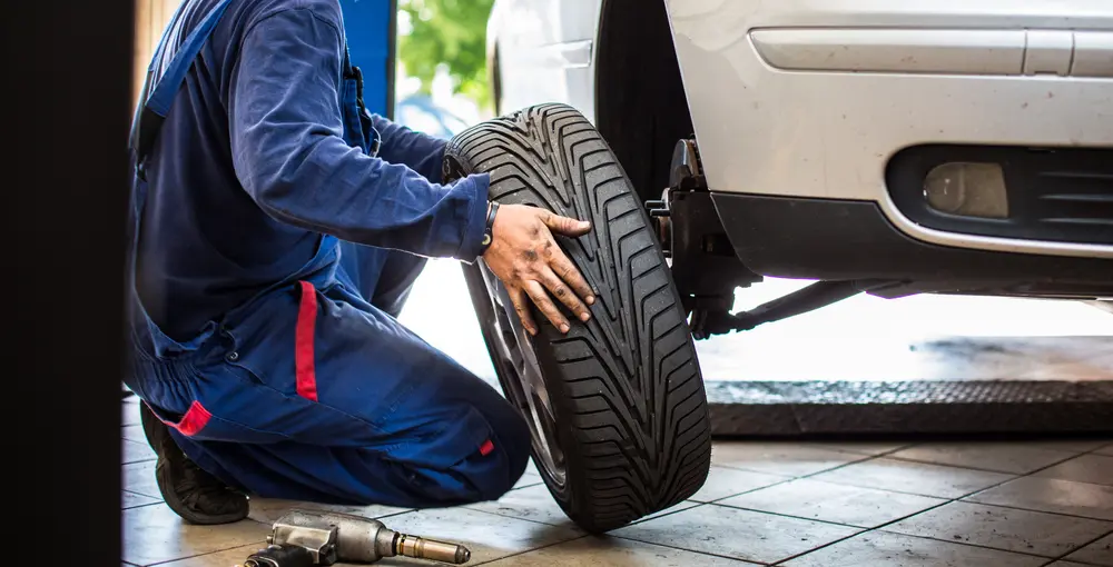Mechanic installing a tire on a vehicle in an auto repair shop, highlighting essential tire services for vehicle safety and performance.