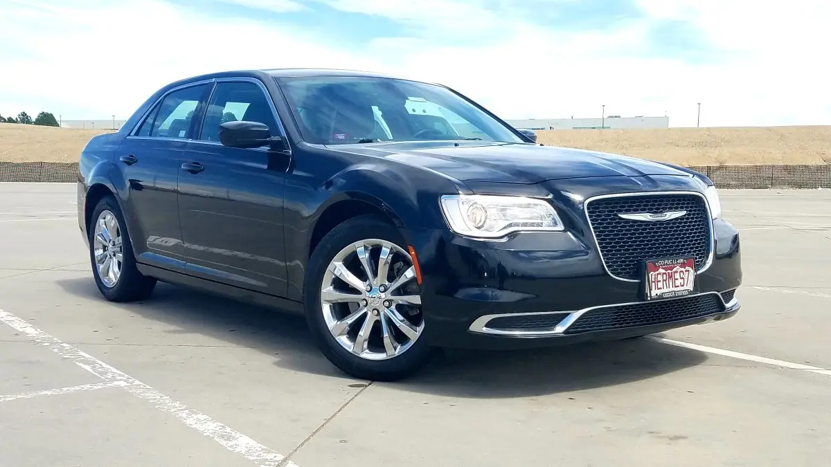 Black Chrysler 300 sedan parked in an open lot, showcasing its stylish design and chrome wheels, relevant to expert Chrysler service and repair in Dyersville, IA.