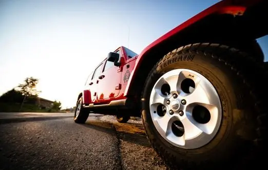 Red all-wheel drive vehicle parked on a road, showcasing tire tread and vehicle details, relevant to winter vehicle maintenance and repair services in Dyersville, IA.