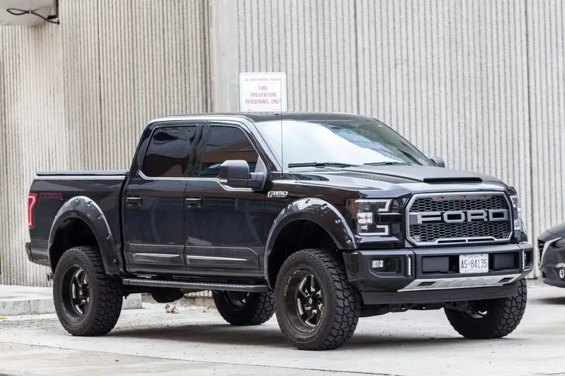 Black Ford F-150 truck parked in an urban setting, showcasing its rugged design and off-road capabilities, relevant to Ford car maintenance tips.