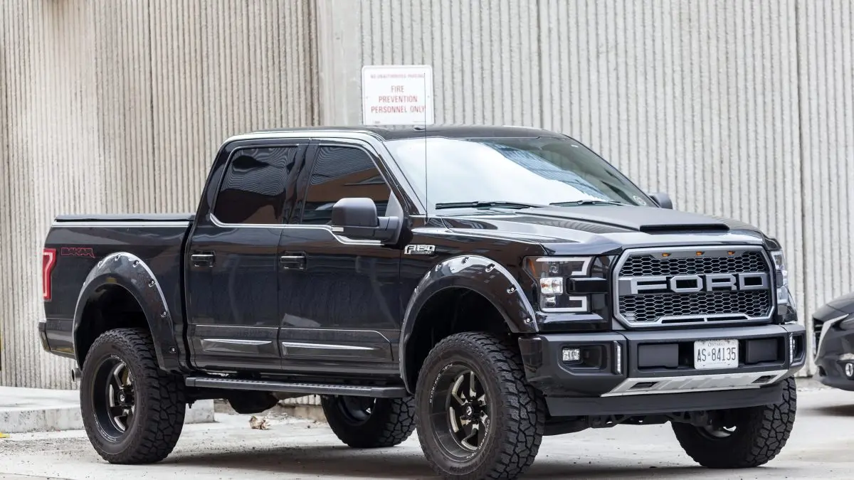 Black Ford F-150 truck parked, showcasing rugged design and off-road tires, relevant to Ford vehicle maintenance tips.