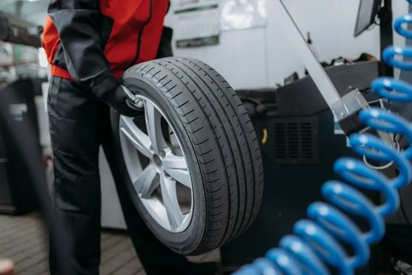 Automotive technician holding a tire, showcasing tire services related to alignment, balancing, and rotation at Deutmeyer Auto Advantage.