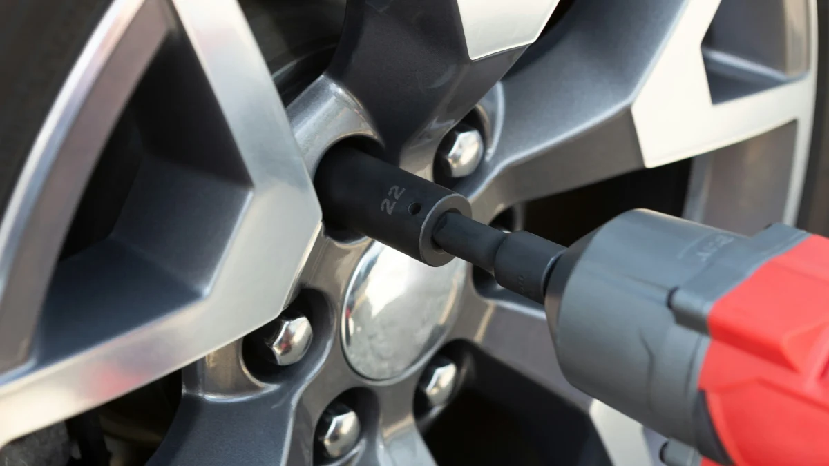 Close-up of a tire wrench applying torque to a lug nut on a vehicle wheel, illustrating tire maintenance and safety practices.