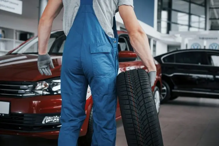 Mechanic holding a tire tire at the repair garage. wheel alignment