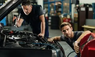 Two mechanics repairing air conditioning system in auto repair shop. Two mechanics repairing air conditioning system in auto repair shop.