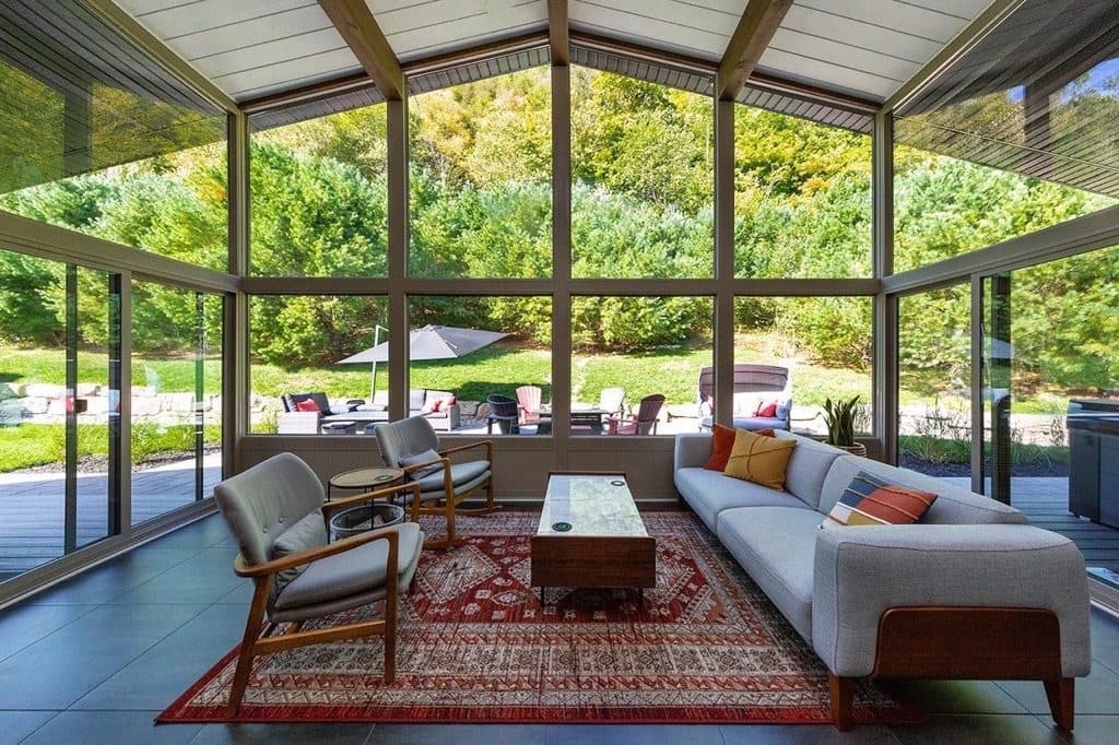 Sunrooms Living Space Sunrooms promo showing a cathedral-style sunroom opening to a large patio and green outdoor space – available from Sutton’s in Springfield IL