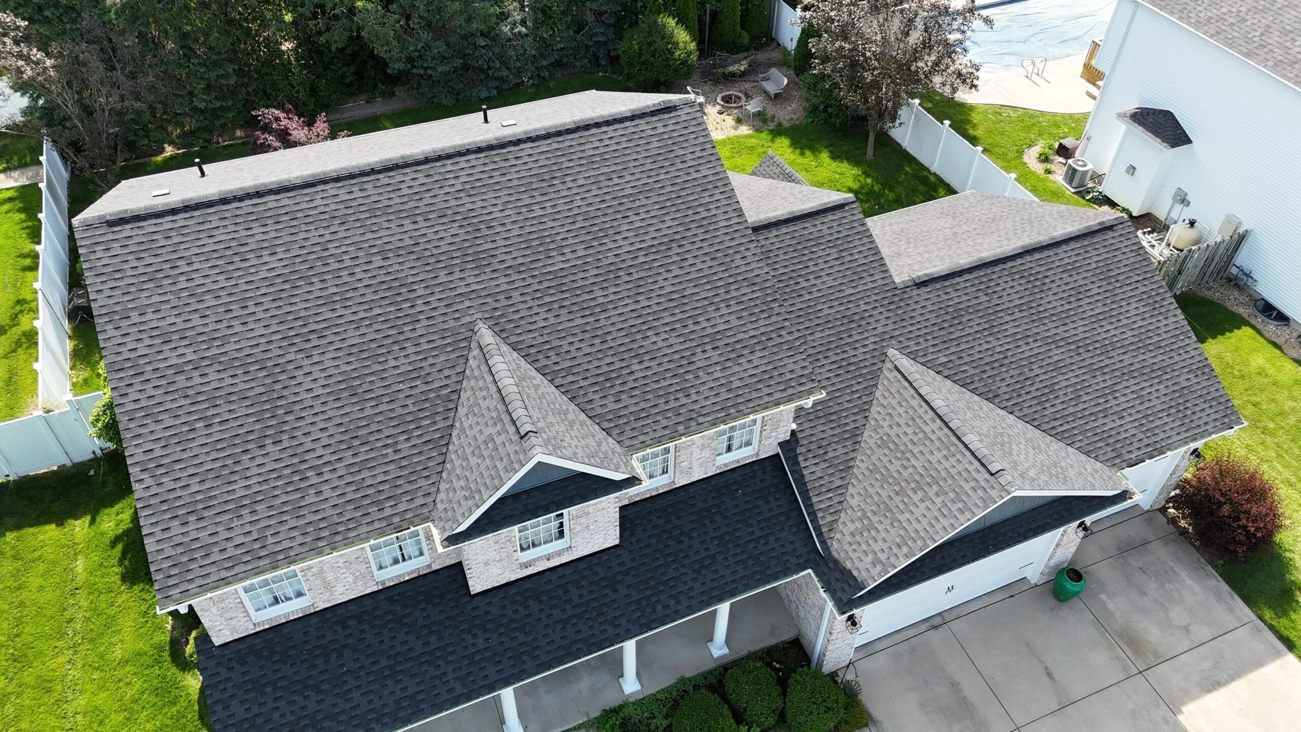 Photo showing the back of a single-story home with a custom sunroom and newly poured concrete patio installed by Sutton’s in Springfield, Illinois. Sutton’s specializes in building sunrooms, decks, patios, roofing, siding, windows, and full-scale remodeling projects with trusted craftsmanship since 1946.
