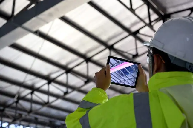 Construction Civil Engineer use technology software through tablets to scan building construction and inspection to show augmented reality in work, Building information model or BIM concept