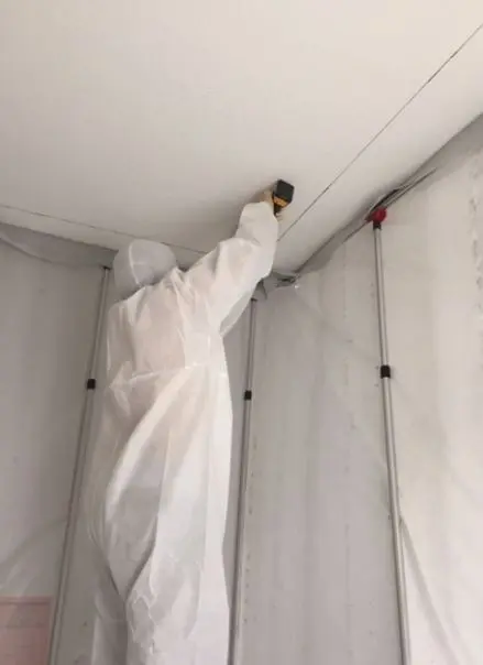 , Why DIY Mold removal is not safe, Titan Restoration Construction worker wearing protective gear attending to mold in ceiling