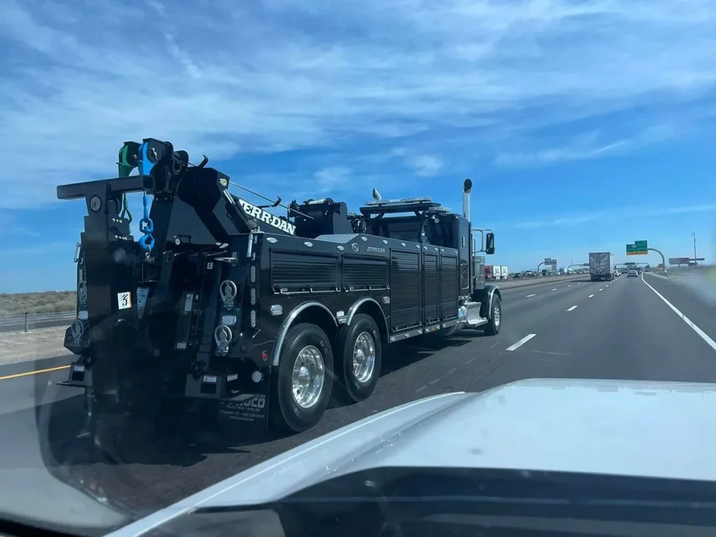a black tow truck on a road