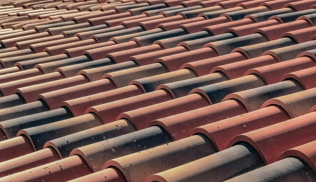 Roofer inspecting a tile roof under Tucson sun for routine maintenance and repair