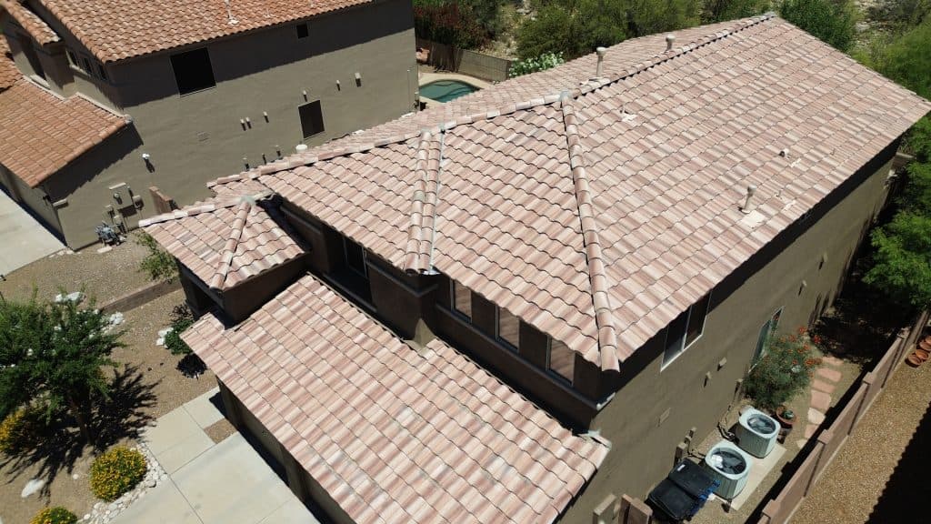 Close-up of damaged shingle roofing on a Tucson home, showing curling edges and granule loss due to sun and storm exposure