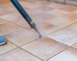 Steam grout cleaning tool treating tile floor grout in Tucson home