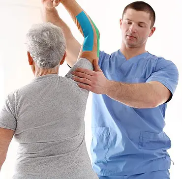 Physical therapist or physiatrist performing gentle shoulder range-of-motion exercise on senior female patient, illustrating musculoskeletal rehabilitation and holistic treatment at Multi-Specialty Pain Management