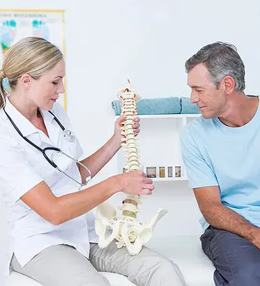 Doctor explaining spinal anatomy using a model to a patient during pain management consultation at Multi-Specialty Pain Management