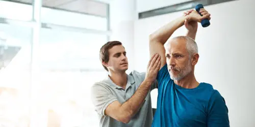Florida injury doctor guiding an older male patient through shoulder rehabilitation exercise with a light dumbbell
