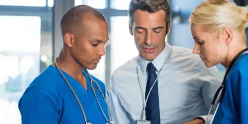 Team of Florida injury doctors in blue scrubs reviewing a patient case file with a supervising physician at Select Injury Doctors in Florida.
