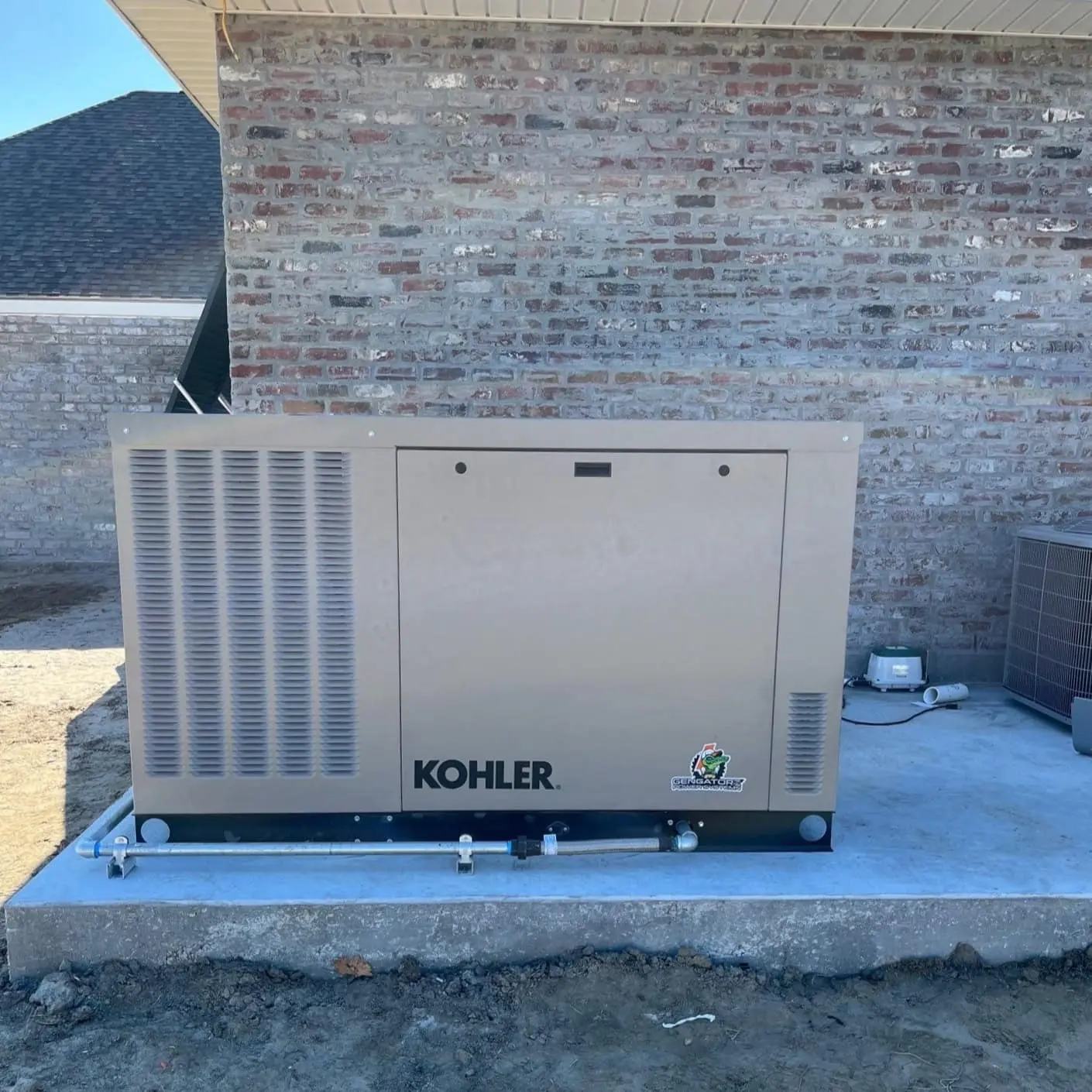 kohler generator Kohler generator installed on concrete slab next to brick building