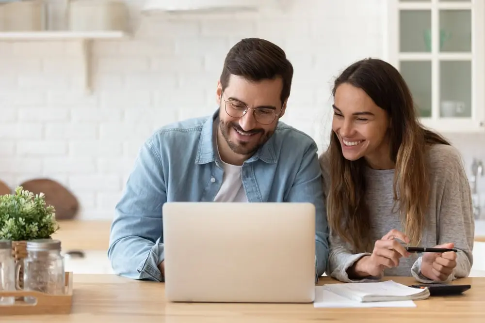 Happy couple working at desk on lap top