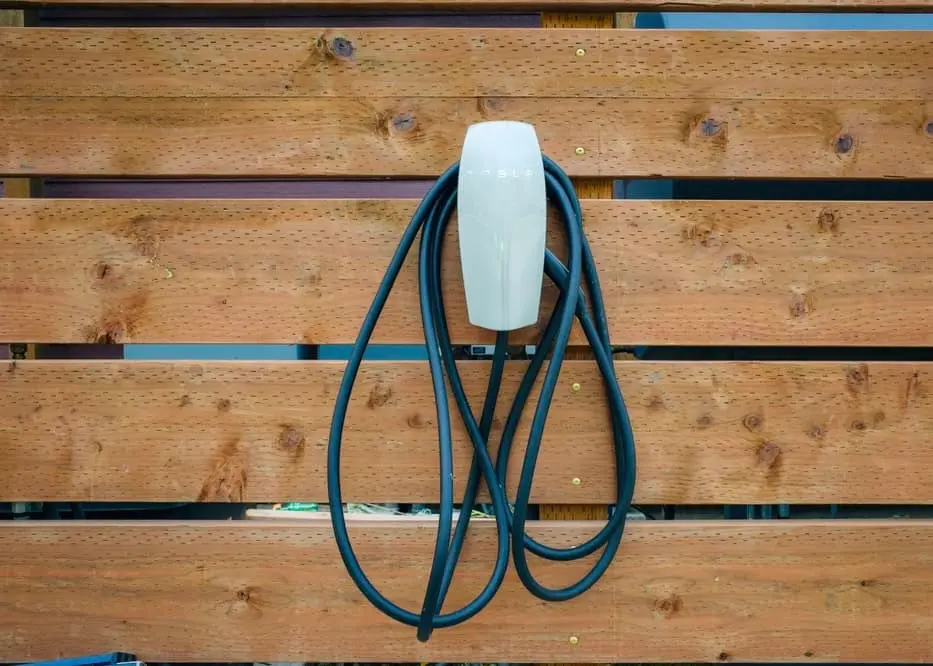 Home EV charger mounted on a wood wall with the cable coiled