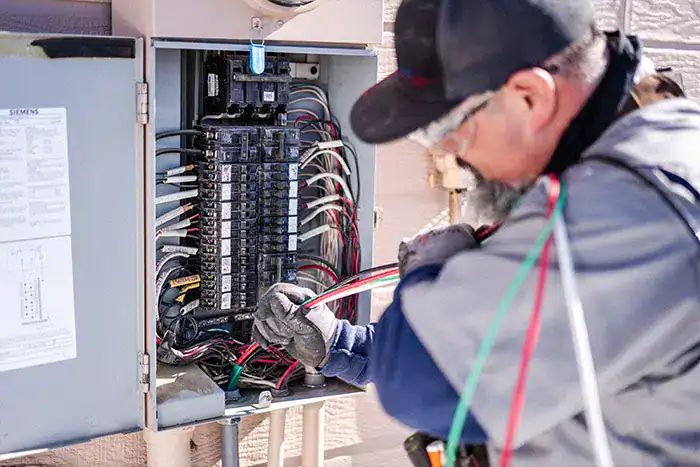 Electrician testing wiring inside an open residential electrical panel