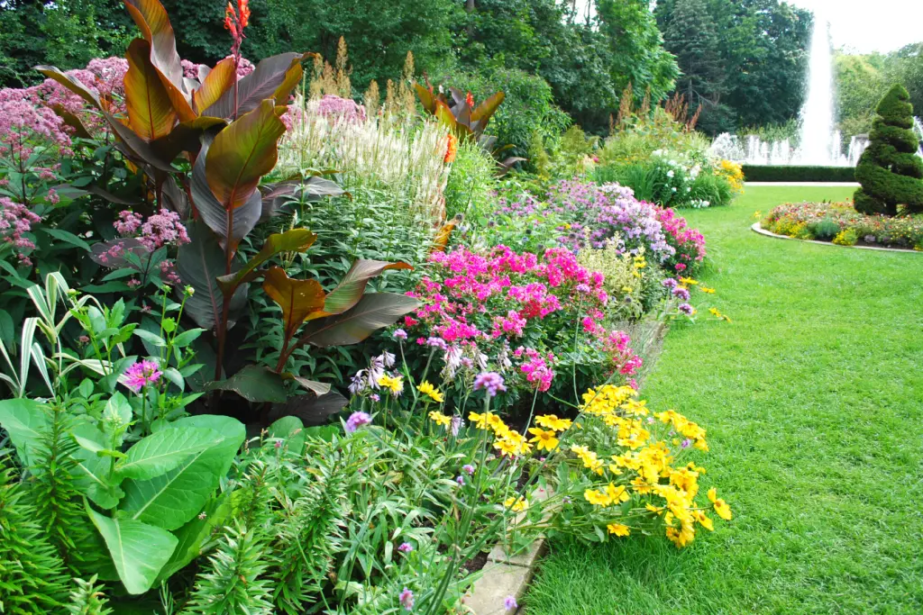Lush garden with colorful flowers, green grass, and a fountain in the background. Takeoff-Moving Toronto