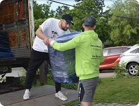 Movers carefully load a wrapped item from a truck, showcasing professional moving services. Takeoff-Moving Toronto