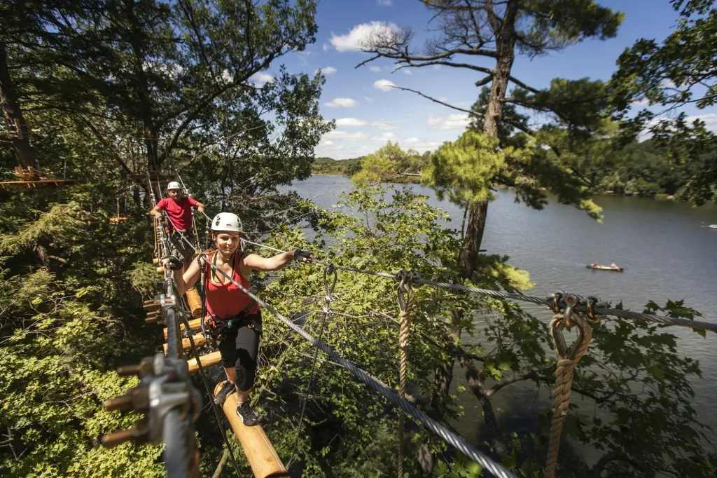 Woman on high ropes course over water with trees and blue sky Takeoff-Moving Toronto