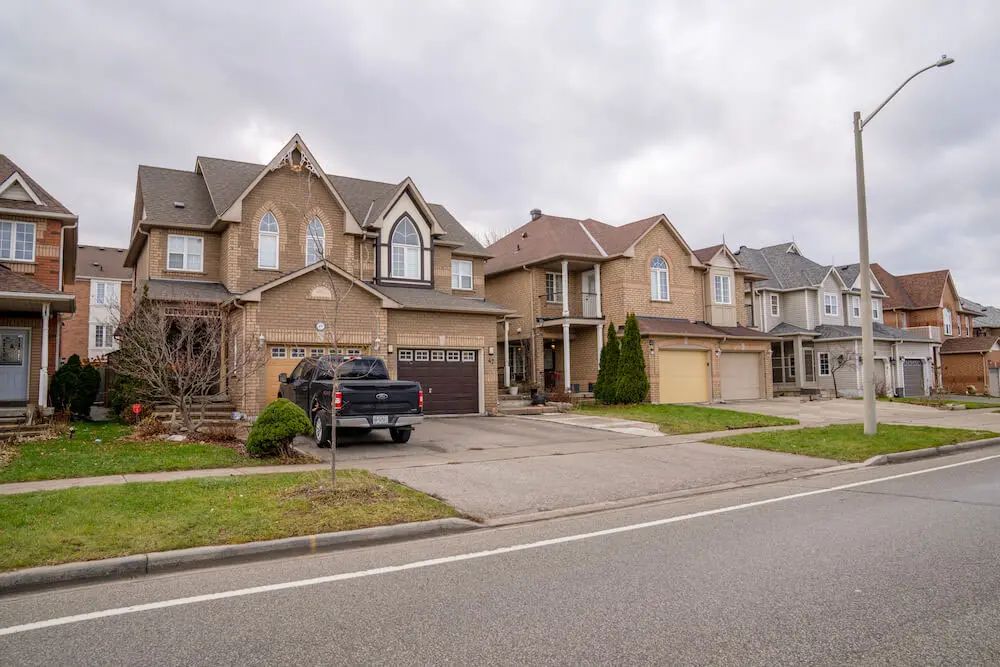 Suburban street with row of two-story brick houses and parked cars. Takeoff-Moving Toronto