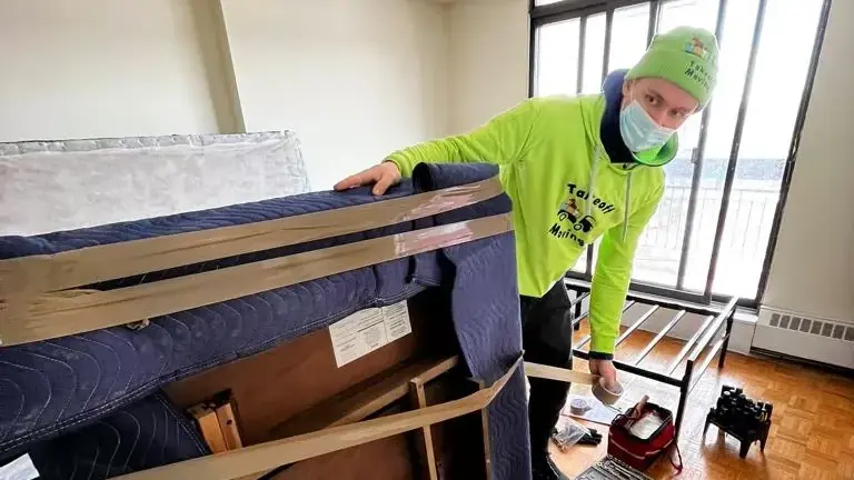 Moving crew member in neon green wraps a mattress for transport. Takeoff-Moving Toronto