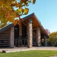 Rustic log cabin entrance with stone pillars and autumn foliage. Takeoff-Moving Toronto