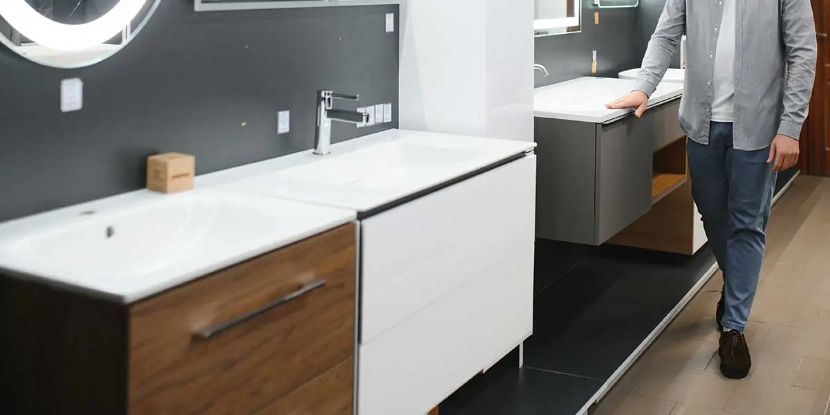Bathroom cabinet material selection A man examines modern vanities in a showroom, highlighting options for choosing the right material for your bathroom cabinets.