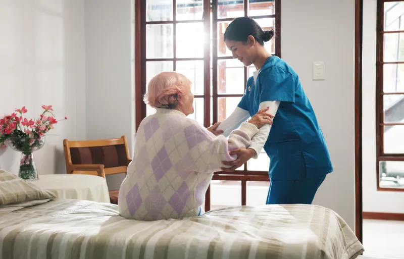 caregiver helping resident get up from bed caregiver helping resident get up from bed