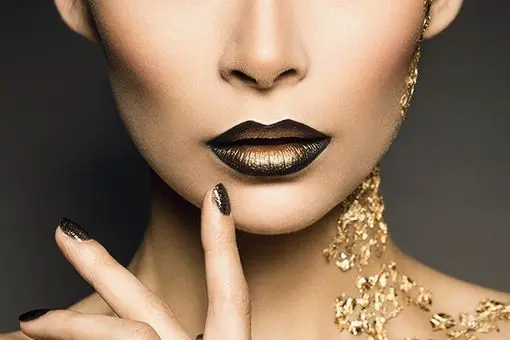 A woman's black and gold lips. with gold running down her neck