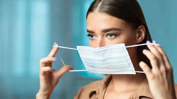 a woman putting on a mask
