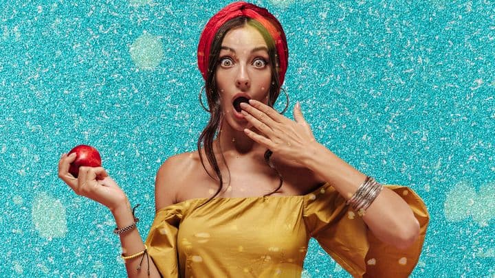 a woman who is surprised holding an apple