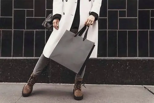 a woman standing holding a bag