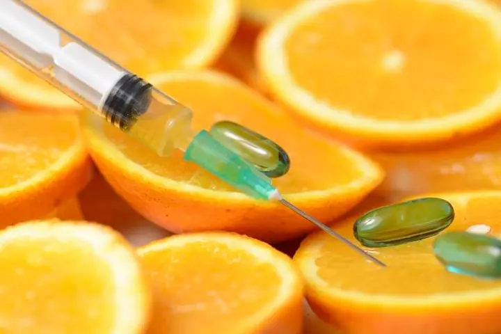 Slices of oranges with pills and a needle