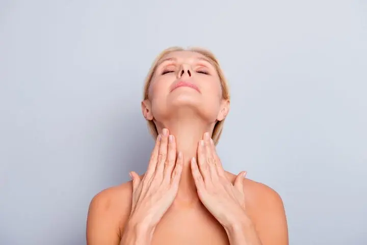a woman looking up placing her hands on her throat