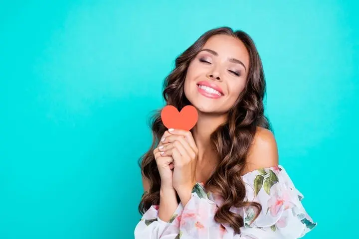 Close up portrait of nice, cute, lovely woman hold one small paper card in hands isolated on shine turquoise background with copy space for text