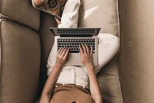 A woman on her laptop setting on her coach