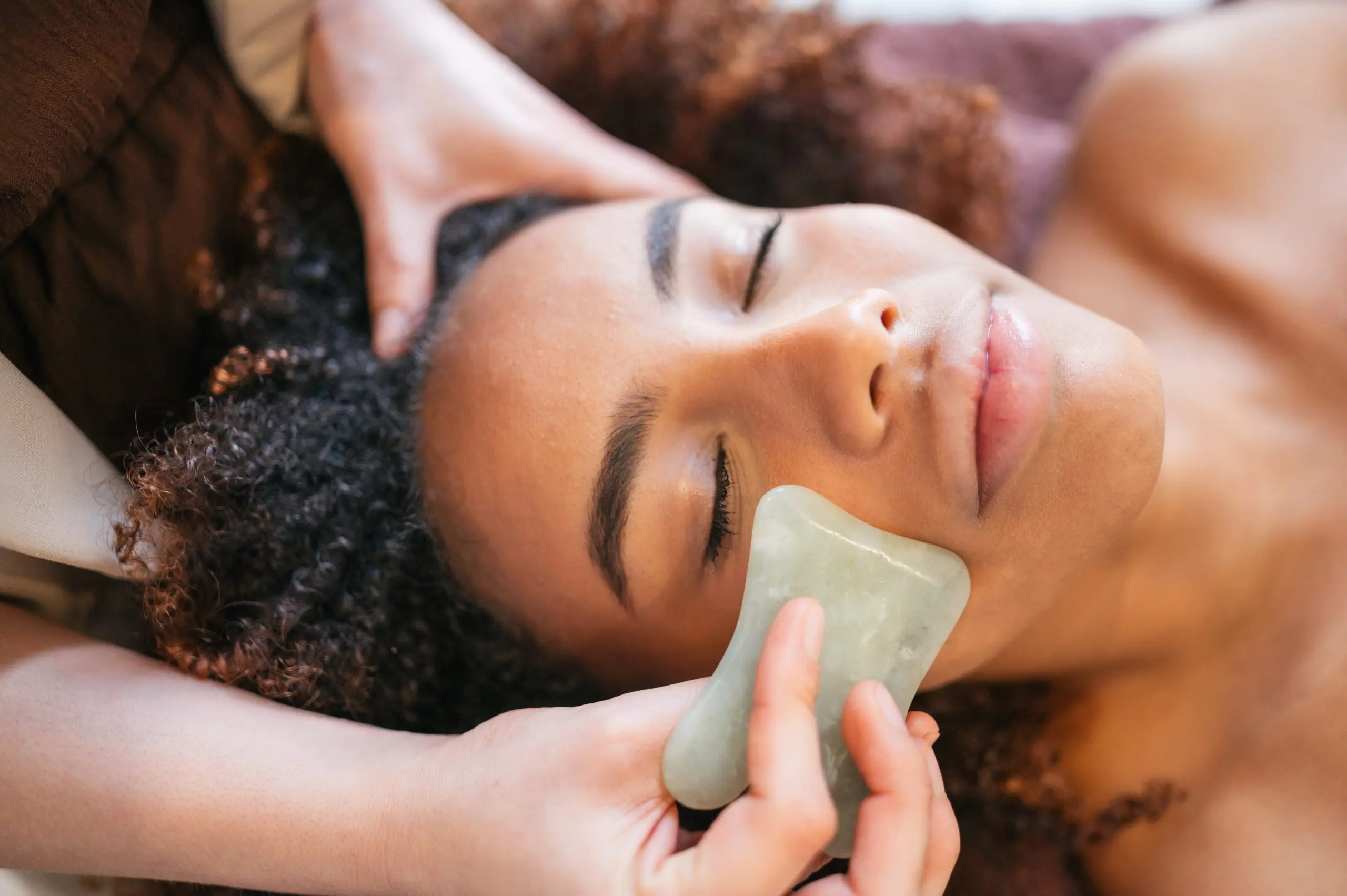 Woman enjoying relaxing gua sha facial treatment at spa