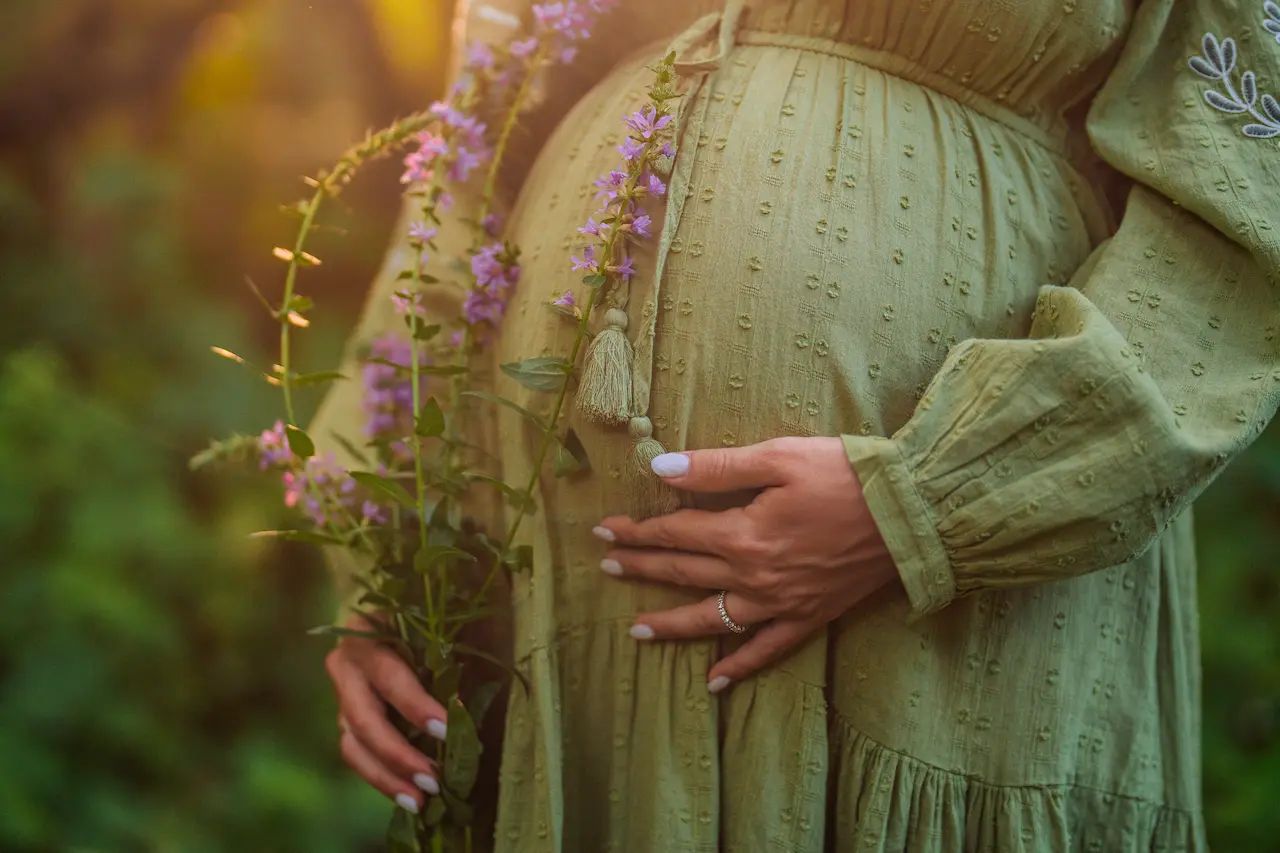 expecting-woman-holds-flowers-in-golden-sunlight