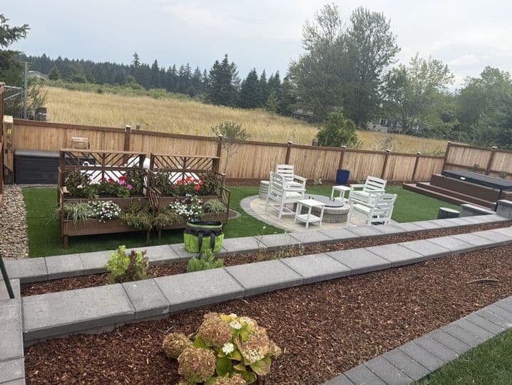 Multi-level backyard with paver patio, raised garden beds, and seating in Winlock, Washington