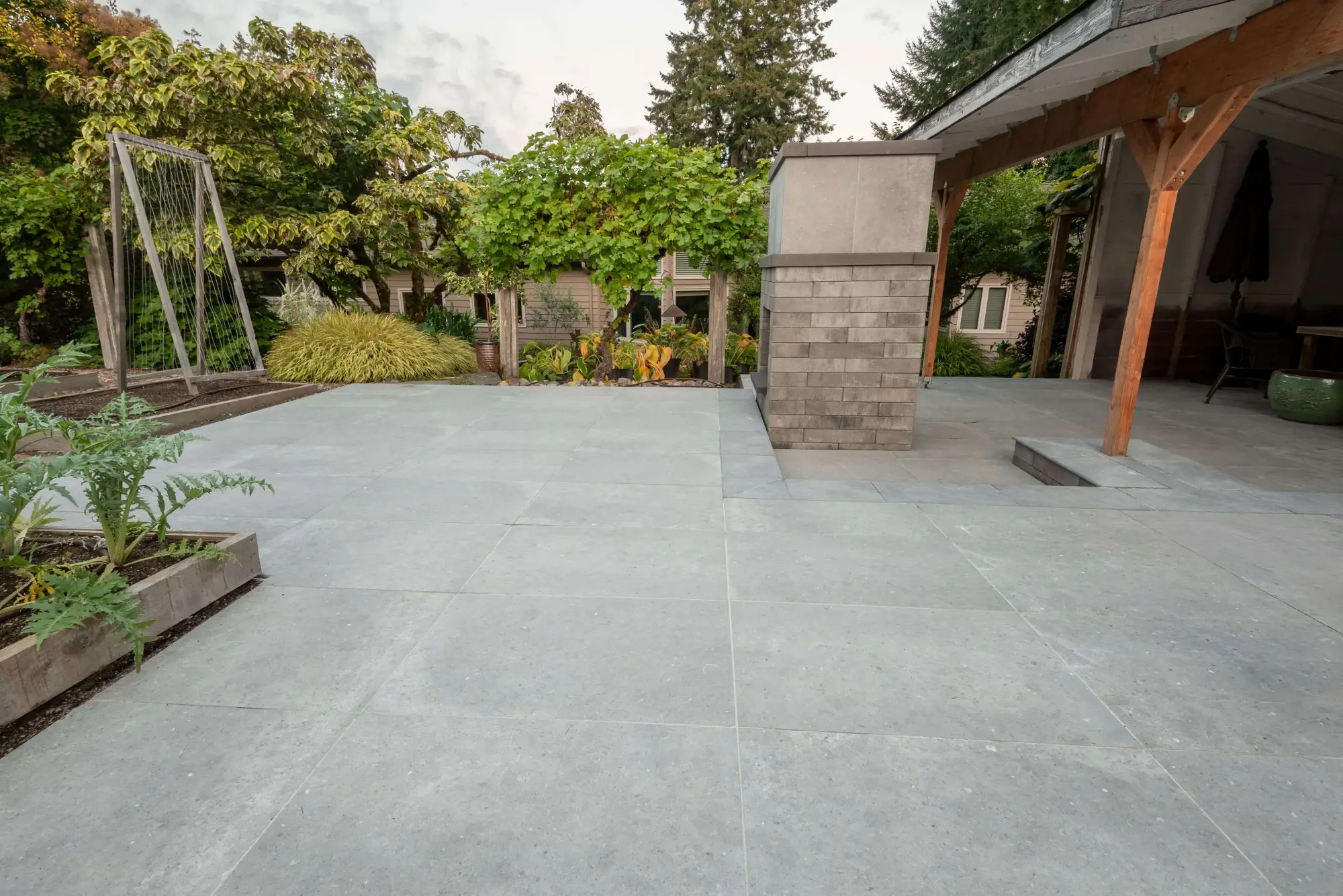 Outdoor porcelain tile installation on a modern patio surrounded by garden landscaping