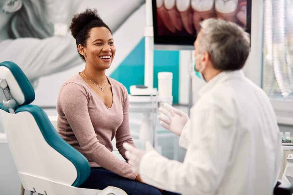 dentisti showing patient how to cover a cavity on front tooth